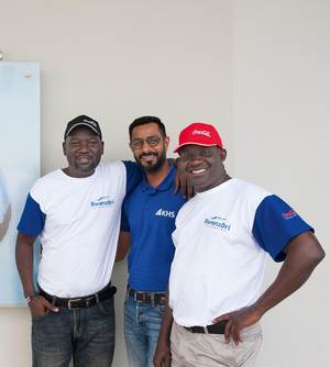 Zufrieden mit dem Ergebnis ihres Teamworks: Edward Ojede (links) und Innocent Obong, beide CCBA, nehmen KHS-Key-Account-Service-Manager Dilesh Karia in ihre Mitte.