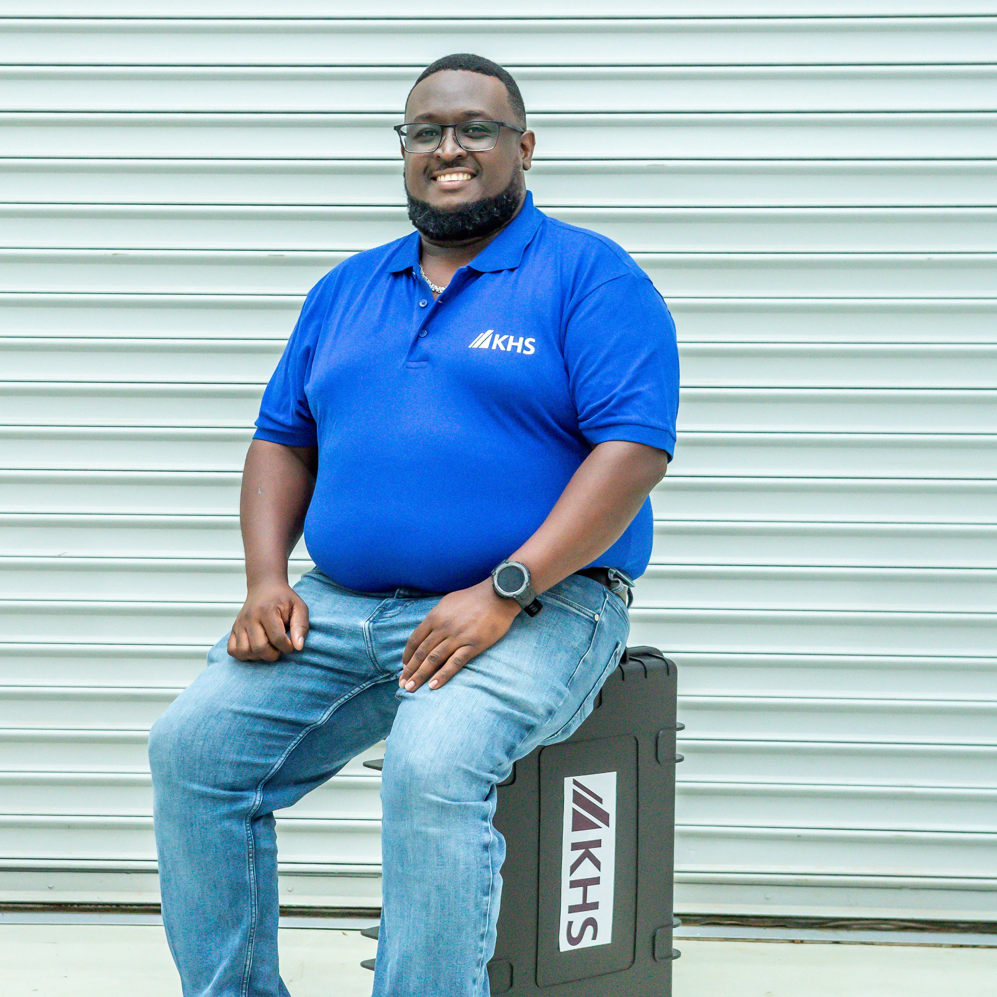 Matthew Ndolo sits on packages on an assembly case