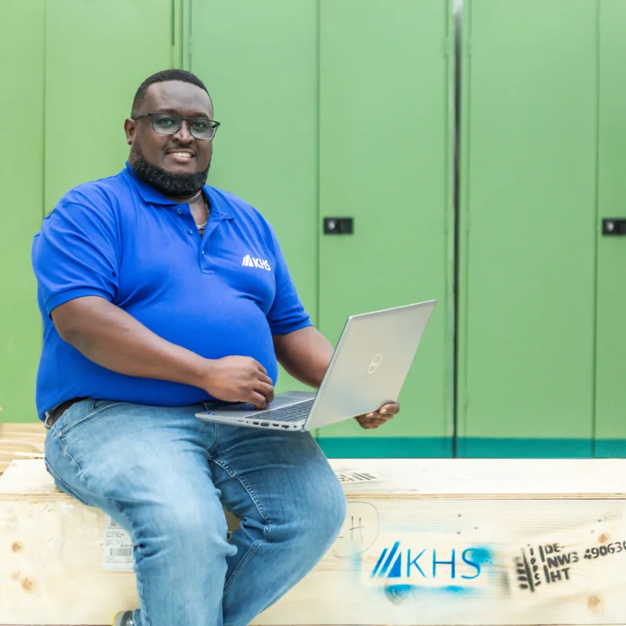 Matthew Ndolo sits on packages in front of a green metal cupboard