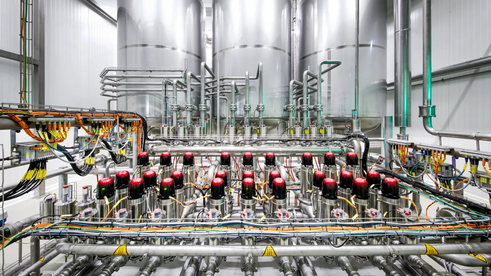 The picture shows 3 beer storage tanks in the background with a fully automatic valve node in the foreground.