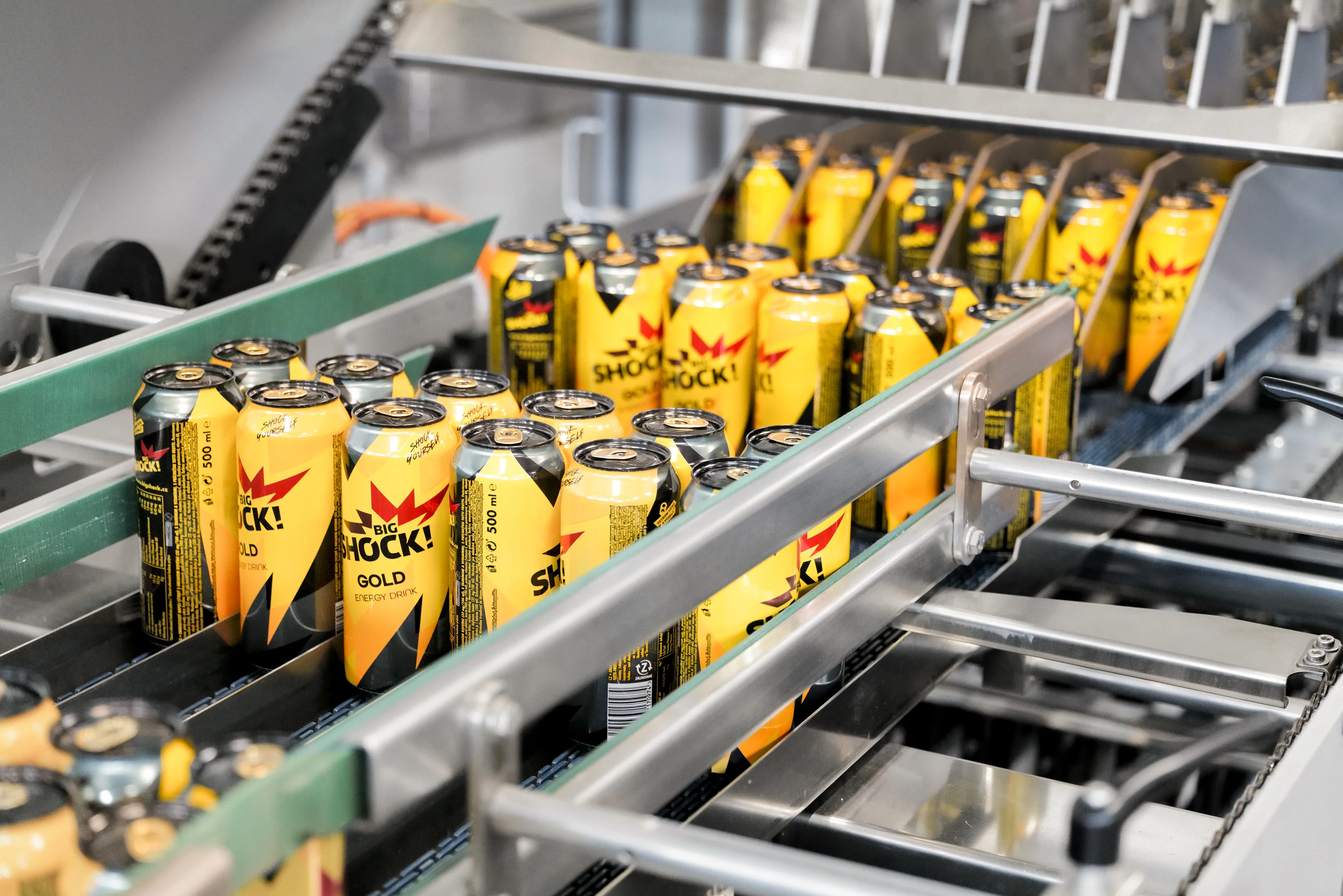 Yellow and black beverage cans are transported on a conveyor belt on the Innopack Kisters TSP machine