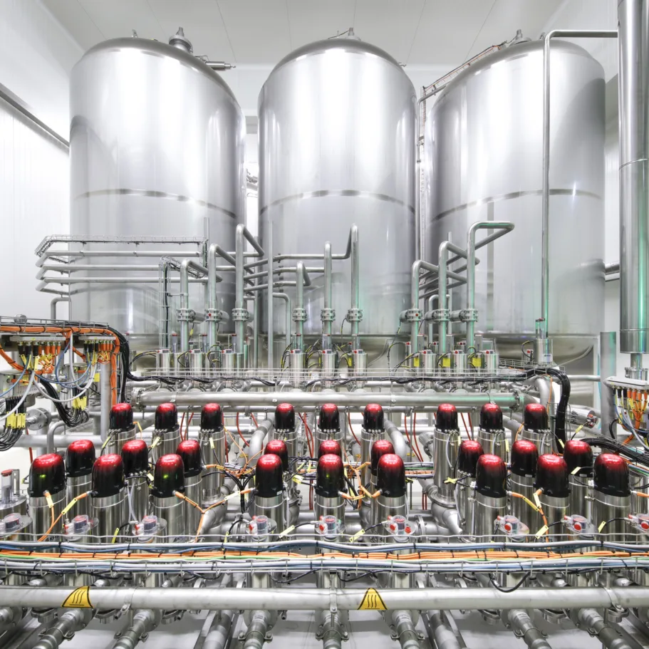 The picture shows 3 beer storage tanks in the background with a fully automatic valve node in the foreground.