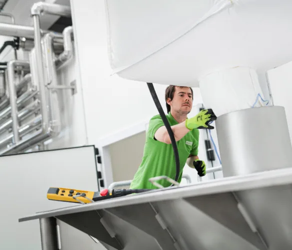 A BOFILLEX employee empties a large bag of sugar into a funnel below.